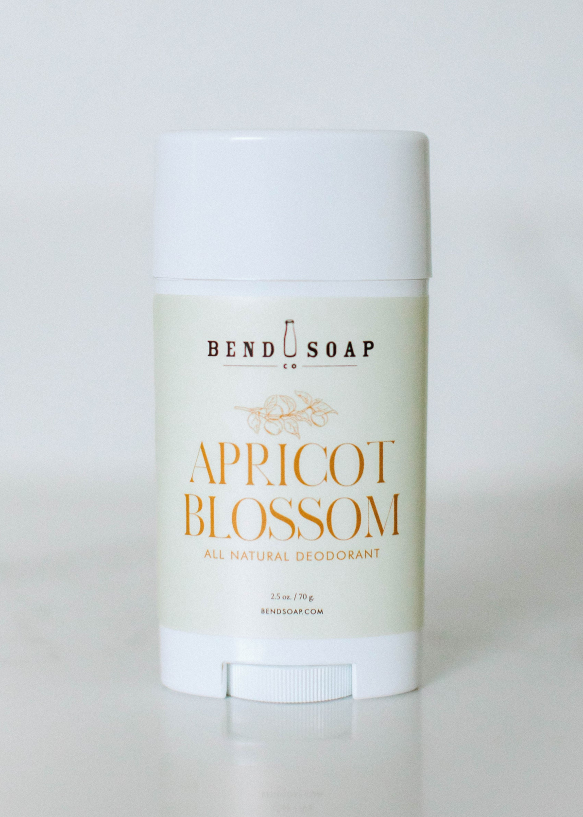 A white stick of Bend Soap all natural deodorant with an "Apricot Blossom" label, displayed upright against a plain, light background.